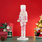 Casse-noisette musicien rose tenant un tambour et des baguettes, fond rouge festif
