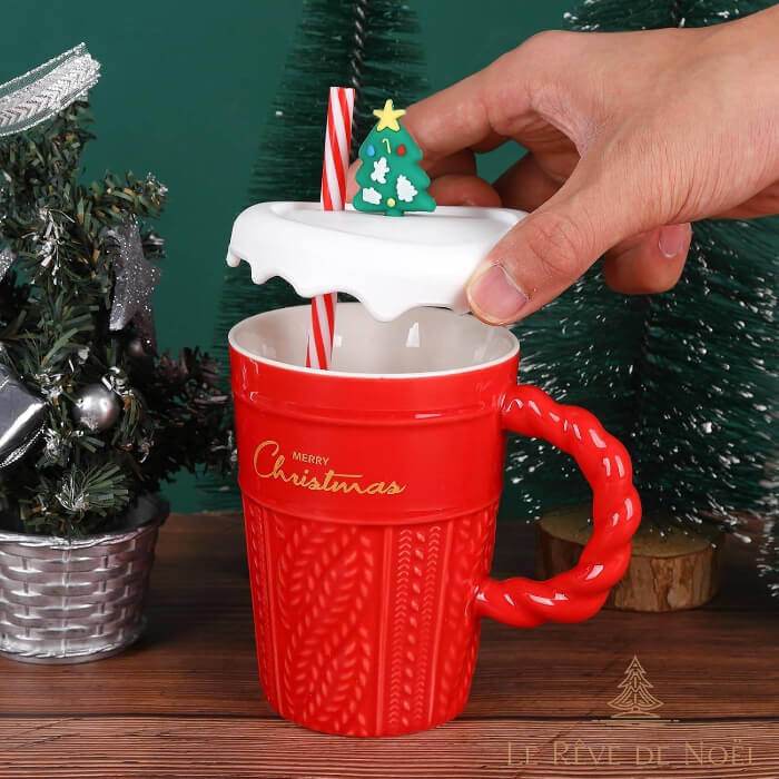 Une main soulève le couvercle du mug rouge, laissant voir la paille rayée dans la tasse vide