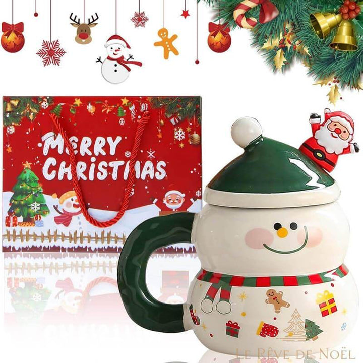 Mug en forme de bonhomme de neige, couvercle bonnet vert surmonté d'un Père Noël, posé près d'un sac cadeau