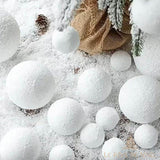 Boules de Noël enneigées de tailles variées éparpillées dans la neige, près d'un sac en toile de jute