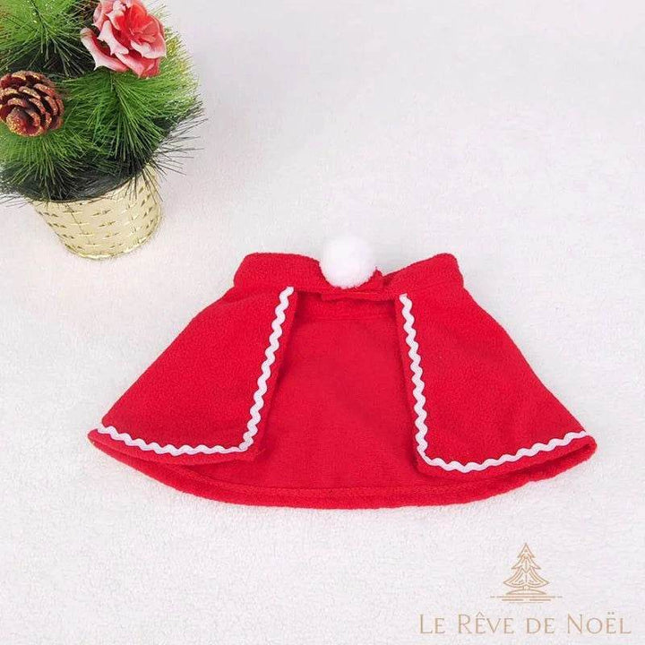 Cape rouge pour animal avec pompon blanc et liseré blanc, posée à plat seule sur fond clair