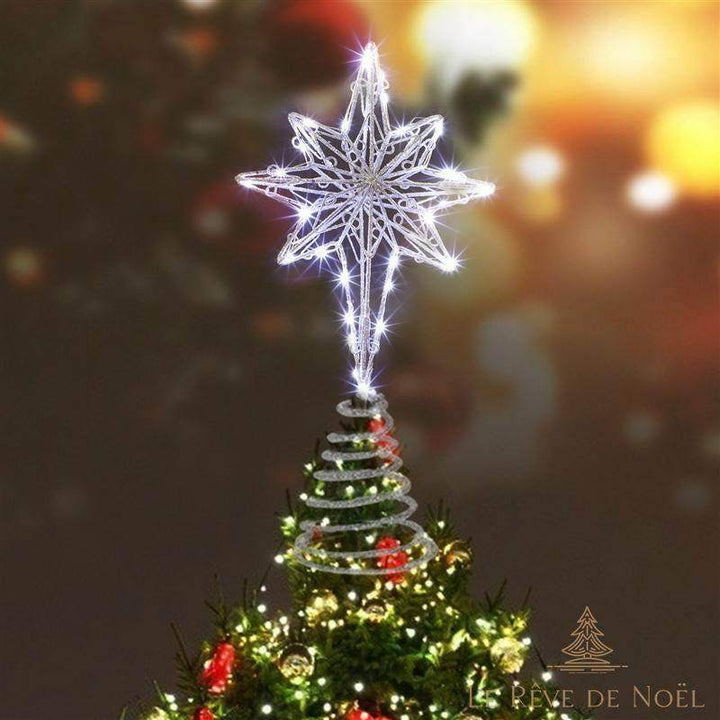 Cimier étoile argenté allumé au sommet d'un sapin, lumière blanc froid, fond flouté sombre