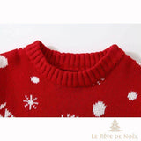 Col côtelé d'un pull de Noël bébé rouge en gros plan, pois et flocons de neige blancs tricotés