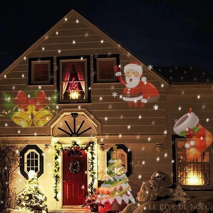 Façade de maison la nuit avec Père Noël, cloches et sapin projetés en motifs lumineux colorés