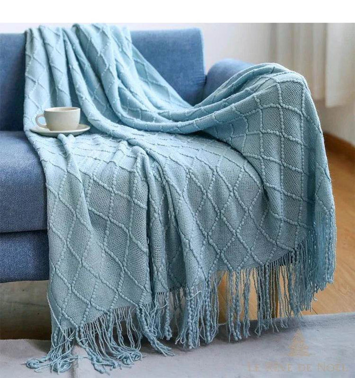 Plaid de Noël bleu ciel pâle drapé sur un fauteuil bleu, tasse de café sur l'accoudoir