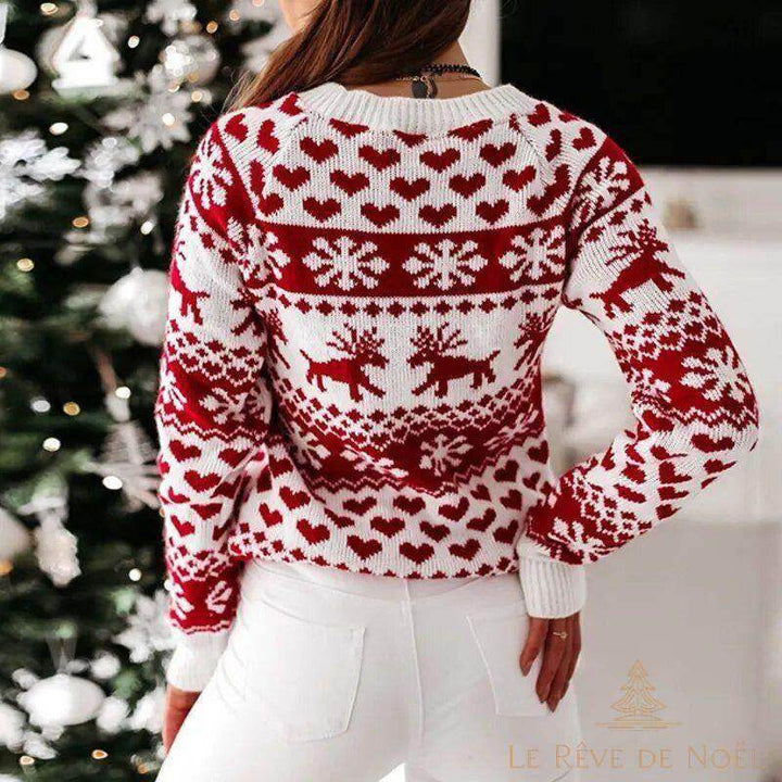 Pull de Noël blanc à motifs rouges de rennes, flocons et cœurs, vu de dos, devant un sapin décoré