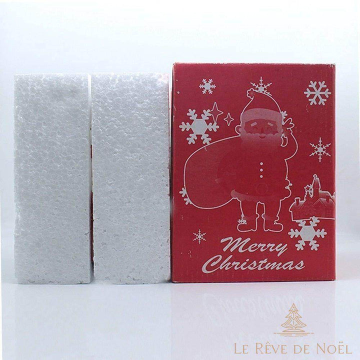Boîte cadeau rouge illustrée d'un Père Noël, posée près de blocs de calage en mousse