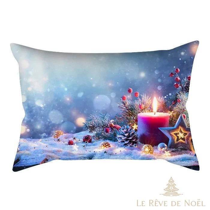 Housse de coussin illustrée d'une bougie rouge allumée sur fond bleuté enneigé, avec houx et pomme de pin