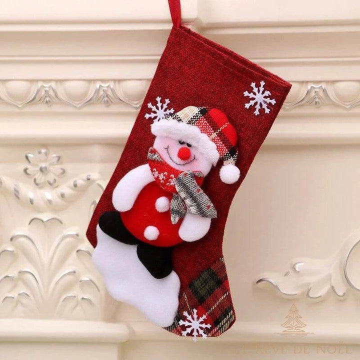Chaussette de Noël rouge à carreaux ornée d'un bonhomme de neige, suspendue à une cheminée