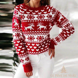 Pull de Noël rouge à motifs blancs de rennes, flocons et cœurs, gros plan de face avec un jean blanc