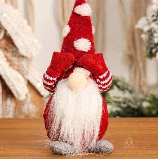 Lutin de Noël rouge, bonnet pointu à pois blancs, mains cachant le visage, longue barbe blanche