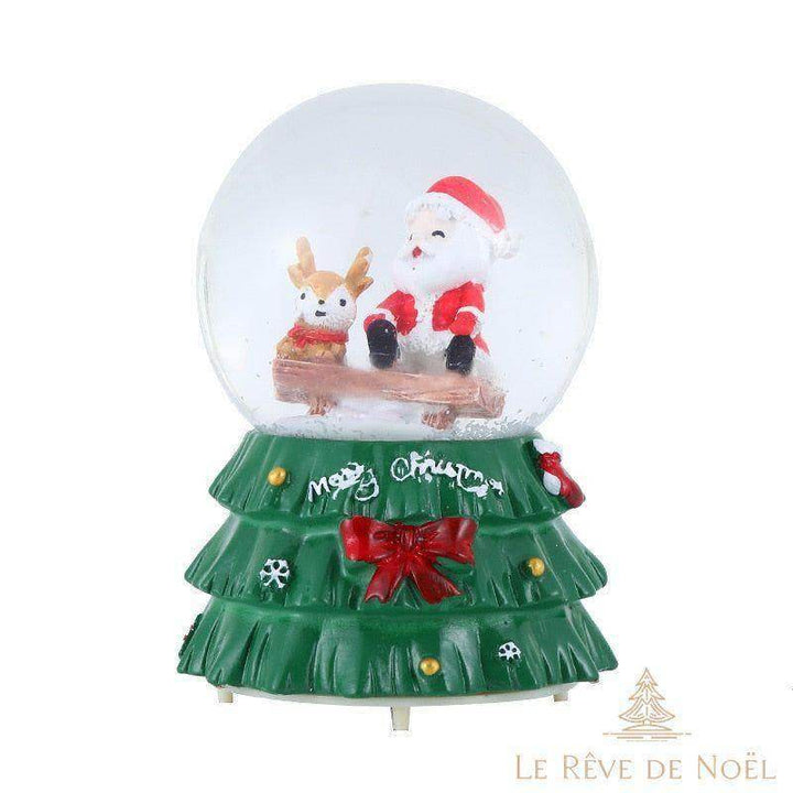 Boule à neige avec Père Noël et renne assis sur une bûche, socle vert en forme de sapin