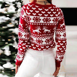Pull de Noël rouge à motifs blancs, vu de dos, la femme se tient devant un sapin décoré