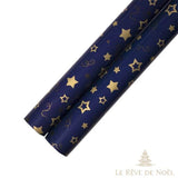 Deux rouleaux de papier cadeau bleu marine à grandes étoiles dorées, extrémités visibles