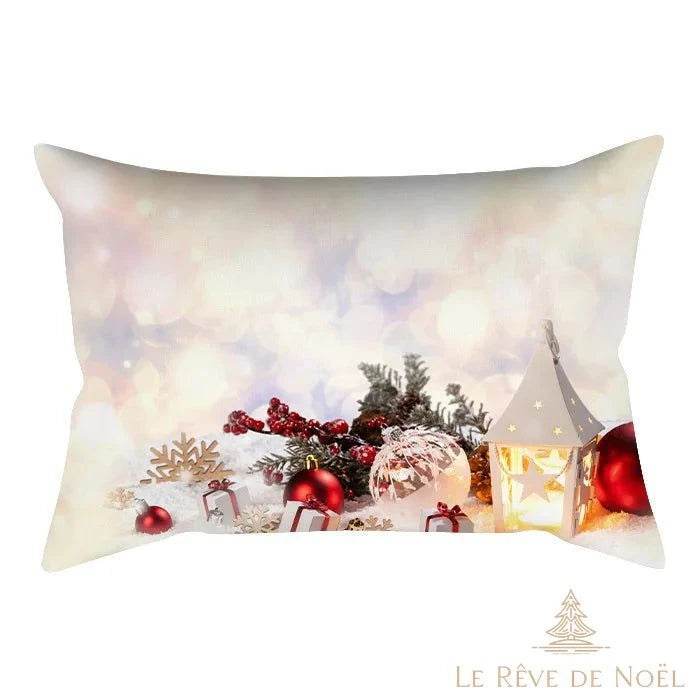 Housse de coussin illustrée d'une lanterne blanche allumée et de boules rouges dans la neige