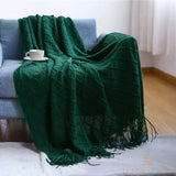 Plaid de Noël vert sapin foncé drapé sur un fauteuil bleu, tasse de café, parquet visible