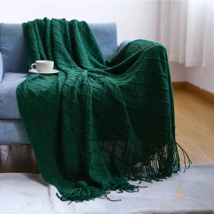Plaid de Noël vert sapin foncé drapé sur un fauteuil bleu, tasse de café, parquet visible