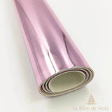 Papier cadeau métallisé rose pâle brillant, enroulé en rouleau montrant l'envers blanc du papier
