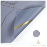 Papier cadeau effet marbre violet pâle grisé, coin replié laissant voir une veine dorée