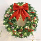 Couronne de Noël avec guirlande lumineuse allumée et nœud rouge, accrochée au mur