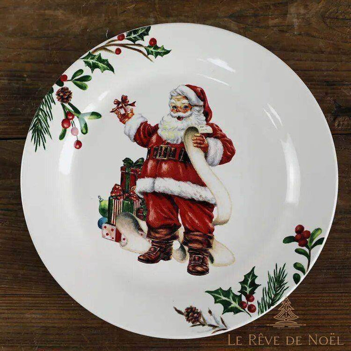 Assiette bordée de houx, Père Noël tenant une clochette et une longue liste, cadeaux à ses pieds