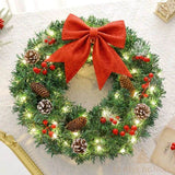 Couronne de Noël lumineuse posée à plat sur un tissu blanc, nœud rouge et pommes de pin