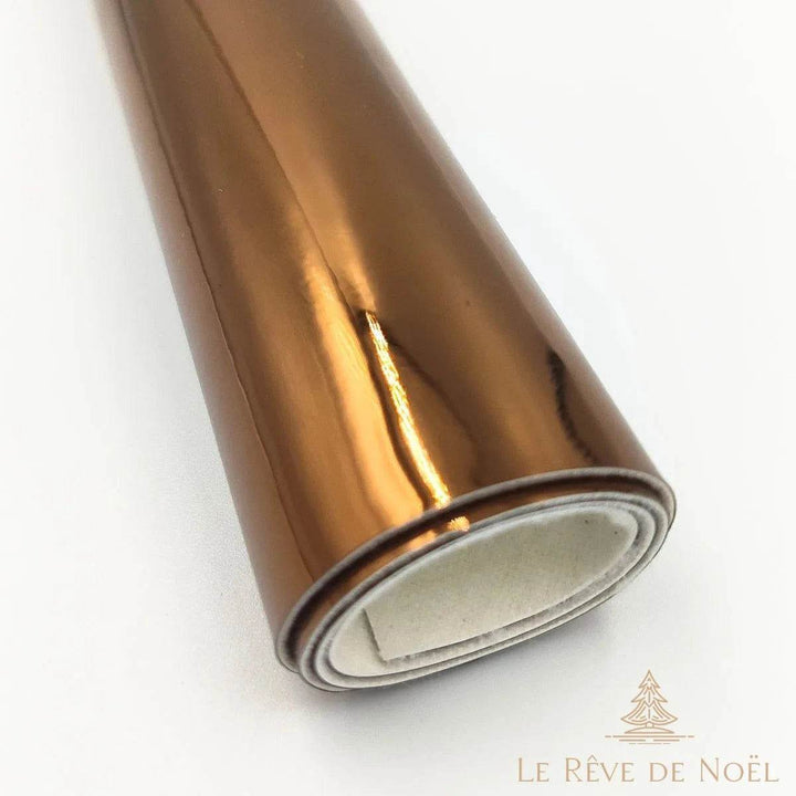 Papier cadeau métallisé marron cuivré brillant, enroulé en rouleau montrant l'envers blanc du papier