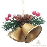 Double cloche dorée de Noël avec pommes de pin et baies rouges sur branche de sapin
