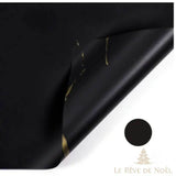 Papier cadeau effet marbre noir, coin replié laissant apparaître des éclats dorés irréguliers