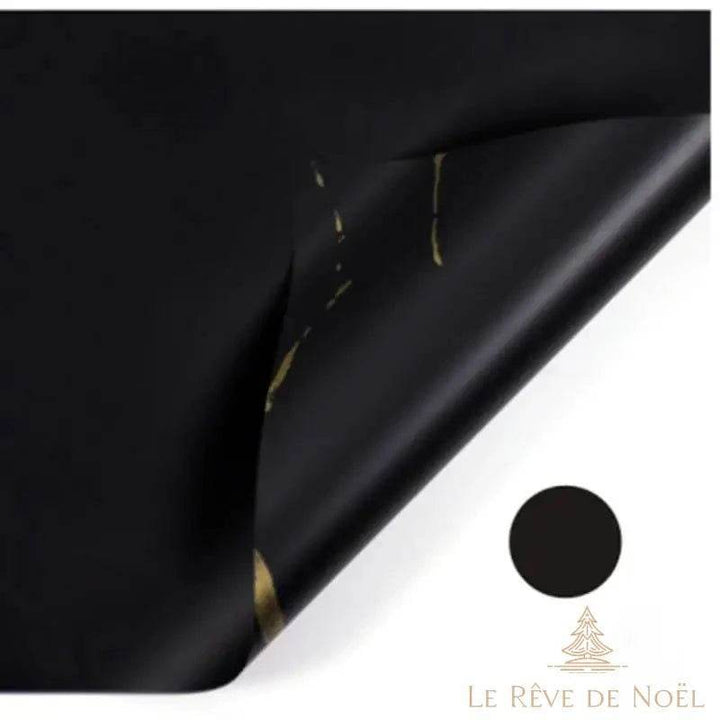 Papier cadeau effet marbre noir, coin replié laissant apparaître des éclats dorés irréguliers