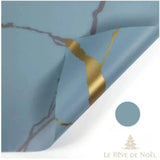 Papier cadeau effet marbre bleu-gris veiné de noir, coin replié révélant une veine dorée