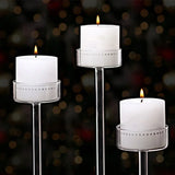 Trois bougeoirs en verre avec bougies blanches allumées, fond sombre et lumières floues