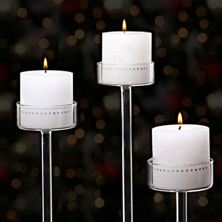 Trois bougeoirs en verre avec bougies blanches allumées, fond sombre et lumières floues