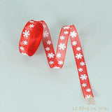 Rouleau de ruban organza rouge à flocons blancs, déroulé en serpentin sur fond gris
