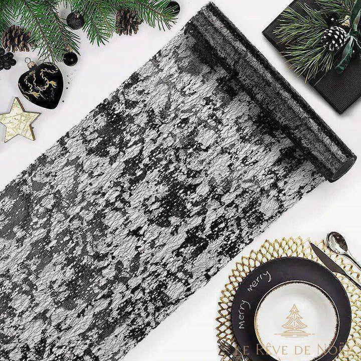 Chemin de table de Noël noir en dentelle déroulé, avec boules noires et assiette dorée