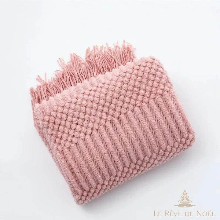 Plaid de Noël rose poudré plié en angle, relief en picots et côtes, franges en haut de l'image