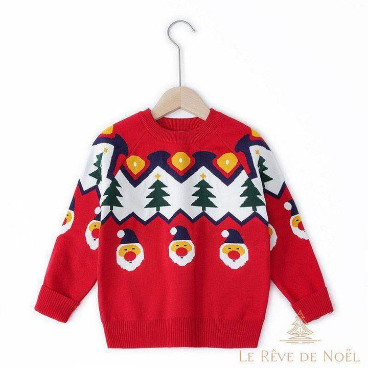 Pull enfant rouge à motif sapins et visages du Père Noël, sur cintre en bois