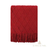 Plaid de Noël en maille rouge à motif losanges, posé à plat, longues franges torsadées