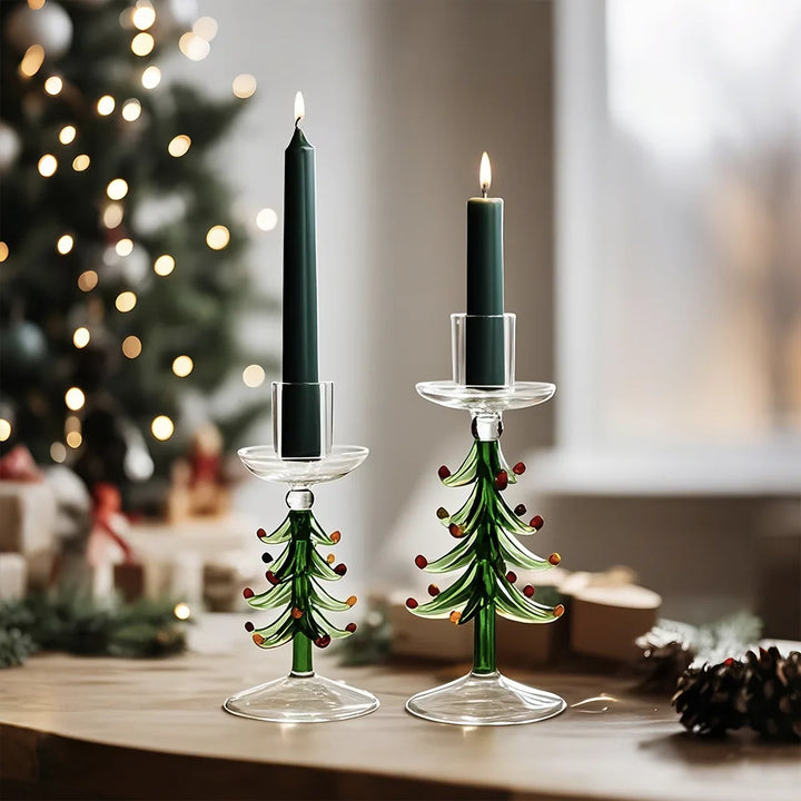 Deux bougeoirs sapin en verre avec bougie vert foncé allumée, sapin illuminé en fond