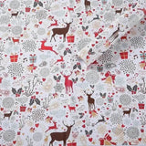 Rouleau de papier cadeau blanc déroulé, silhouettes de rennes bruns et rouges, clochettes dorées