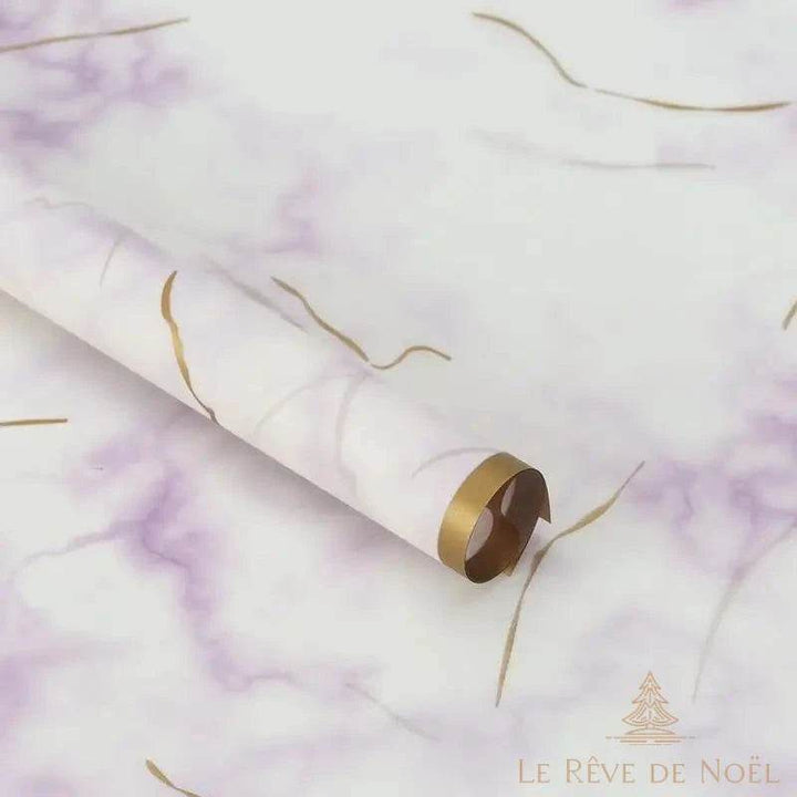 Rouleau de papier cadeau effet marbre blanc et violet, entouré de rubans dorés bouclés