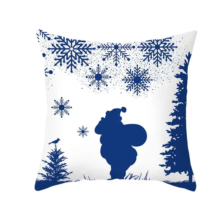 Housse de coussin blanche, silhouette bleue du Père Noël portant sa hotte entre des sapins