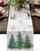 Chemin de table blanc à flocons argentés et sapins peints, dressé avec bougies, verres à vin et branches de sapin