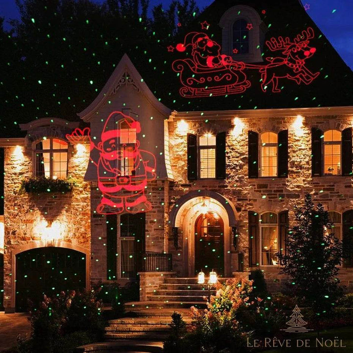 Façade en pierre d'une maison la nuit avec le traîneau du Père Noël projeté en rouge sur le toit