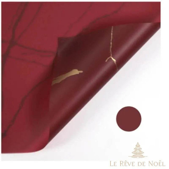 Papier cadeau effet marbre rouge bordeaux, coin replié laissant voir une veine dorée