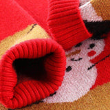 Gros plan sur les poignets côtelés rouges du pull repliés, motif de bonhomme de neige visible