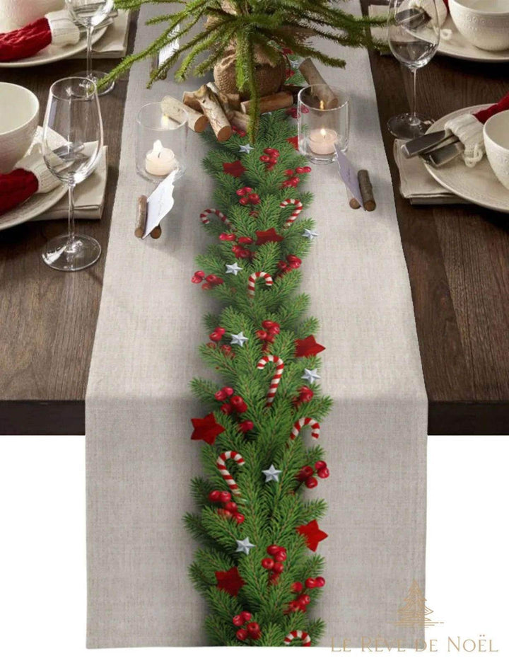 Chemin de table beige avec guirlande de sapin, baies rouges et cannes de bonbon, table dressée