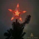 Cimier étoile à LED rouges allumé au sommet d'un sapin, dans une pièce sombre