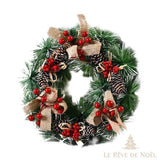 Couronne de sapin avec nœuds en toile de jute, pommes de pin enneigées et baies rouges groupées