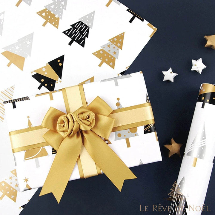 Cadeau emballé dans du papier blanc à sapins géométriques dorés et noirs, nœud en ruban doré